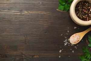 Cooking background, home cooking concept. Spoon, herbs and spices on wooden background, top view, copy space. photo