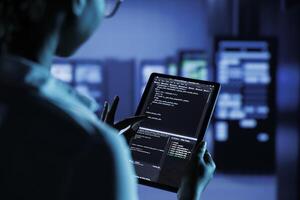 Close up of skilled worker running code and programming on laptop, troubleshooting and upgrading high tech facility designed to accommodate multiple clusters of fully operational server units photo