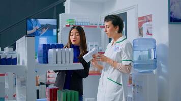 Shopper in chemist shop asking pharmacy employee about product information, trying to find right items on prescription list. Adept druggist helping customer choose fitting sickness medication photo