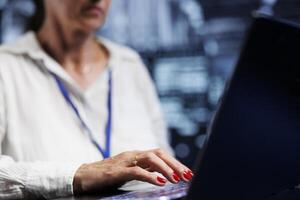 Elderly IT expert in server hub using laptop ensuring valuable data remains shielded from potential threats, safeguarding against unauthorized access and vulnerabilities, close up photo