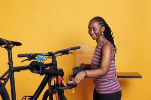 Photograph of youthful black woman preparing professional bike maintenance equipment. Energetic african american lady picking and arranging skilled tools for repairing a broken bicycle. photo