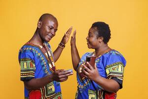 Smiling couple giving high five while making bargain purchase in internet store. Cheerful mid adult boyfriend and girlfriend shopping online and using smartphone and debit card to pay photo