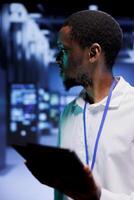 Technician in server hub setting up high bandwidth dedicated multiplayer internet gaming servers to accommodate more traffic from worldwide locations, avoid disruptive lag times and low ping rates photo