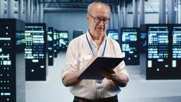 Senior technician looking around high tech data center, using clipboard to crosscheck disaster recovery plan and assess server parts in need of replacement, preventing damages photo