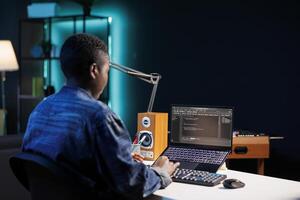 Black female programmer works on her personal computer, managing the database and monitoring network for cyber security. African american woman sitting at desk and using digital laptop for coding. photo