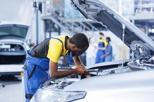 Repairman in car service uses torque wrench to tighten bolts after replacing battery. Certified auto repair shop worker uses professional tools to fix customer automobile photo