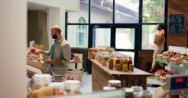 cliente mirando a Fresco verduras en estantería a local cero residuos eco almacenar, elegir a comprar de cosecha propia Produce para sostenible estilo de vida y vegano nutrición. hombre haciendo compras a ecológico tienda. foto