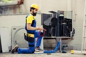 experto técnico oficial para rutina aire acondicionador mantenimiento, montaje manómetro antes de comenzando trabajar. entrenado ingeniero comprobación refrigerante fugas líder a reducido enfriamiento eficiencia foto