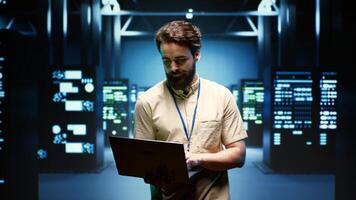 System administrator walking between operational server racks in computer network security data center, ensuring optimal performance. Engineer monitoring energy consumption across components photo