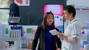 Proficient healthcare practitioner in apothecary helping customer with medical suggestions. Client in dispensary wishing to purchase supplements and vitamins, asking druggist for guidance photo