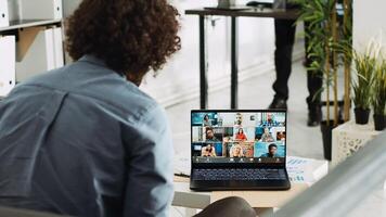 Analyst attends business meeting with department managers, presenting new development vision on videocall conference. Young worker using teleconference to chat in company office. photo