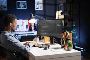 System engineer typing in script code for security and protection, working with programming language at home. African american developer coding and debugging server on terminal window. photo