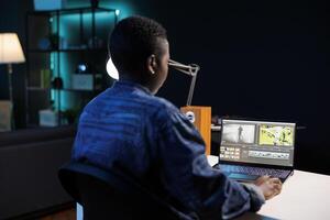 africano americano cineasta absorto en su personal computadora, edición y creando multimedia contenido. imagen demostración negro mujer sentado y trabajando en digital computadora portátil, analizando imágenes. foto