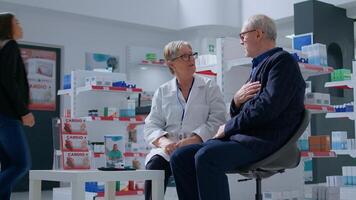 Elderly pharmacist in drugstore with senior patient after finishing annual examination, suggesting him medical products to treat illness symptoms. Older man receiving treatment from specialist photo