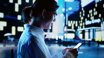 Man strolling around cityscape at night, spending time on social media using smartphone. Businessman walking home from work using phone to make commute more enjoyable, close up photo