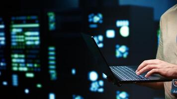 Developer doing yearly system upkeep, imputing data on laptop of required fixing in supercomputers housing advanced data storage hardware supporting important IT workloads photo