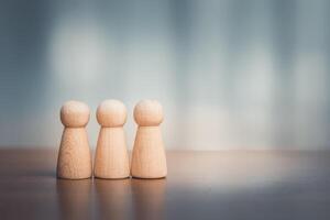 Wooden figures of people standing in a row on a wooden table with copy space photo