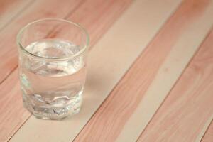 Glass of water on wooden background with copy space, soft focus. photo