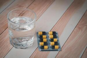 salud esenciales con agua y medicación en de madera mesa foto