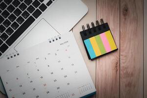 Office desk table with laptop, calendar and indexes sticky note. Top view with copy space photo