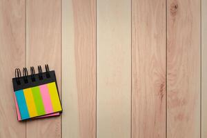 Top view of colorful notepad with copy space on wooden background. photo