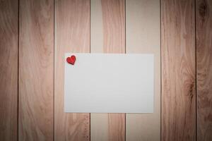 A white paper with a red heart placed on a wooden table photo