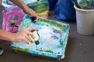 Painter craftsman adds paint to artist tray, workplace with green paint photo