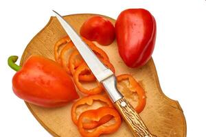 Knife and sweet red ripe pepper on cutting board photo