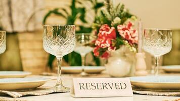 Reserved table in a restaurant with glasses and a red flower photo