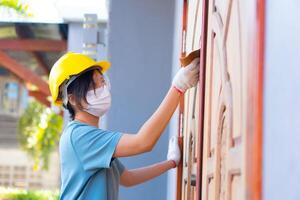 Asian female worker wearing a safety helmet Using sandpaper to polish a wooden door at home. photo