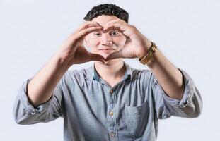 Handsome young man making heart shape with hands isolated. Smiling latin man making heart shape with hands photo