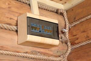 An automatic electric meter in a plastic box for distributing electricity in a village house on a log wall in the hallway. Horizontal photo, close-up photo