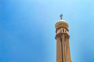 a mosque minaret against a bright blue sky background photo