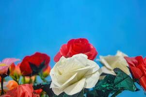 plastic flower bouquets for decoration on a plain blue wall background photo