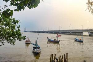 Landscape view of the Suramadu Bridge which stretches over the Madura Strait with several fishing boats photo