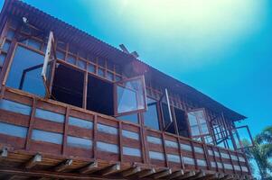 Traditional Japanese style wooden building with open windows against bright blue sky background photo