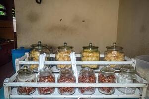 many glass jars filled with crackers and nuts served in a simple Indonesian food stall photo