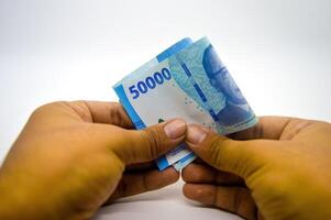 hand holding fifty thousand rupiah notes isolated on white background photo