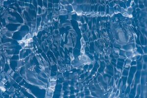 Bluewater waves on the surface ripples blurred. Defocus blurred transparent blue colored clear calm water surface texture with splash and bubbles. Water waves with shining pattern texture background. photo