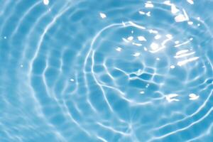 Bluewater waves on the surface ripples blurred. Defocus blurred transparent blue colored clear calm water surface texture with splash and bubbles. Water waves with shining pattern texture background. photo