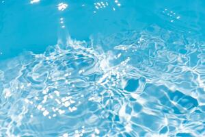 Bluewater waves on the surface ripples blurred. Defocus blurred transparent blue colored clear calm water surface texture with splash and bubbles. Water waves with shining pattern texture background. photo