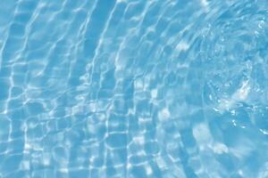 Bluewater waves on the surface ripples blurred. Defocus blurred transparent blue colored clear calm water surface texture with splash and bubbles. Water waves with shining pattern texture background. photo