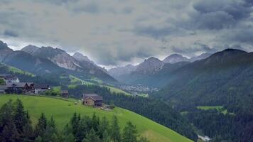 volare al di sopra di un' piccolo montagna villaggio nel un' bellissimo Posizione circondato di il picchi di il dolomiti nel Italia. 4k video