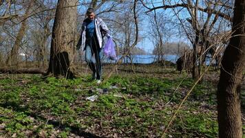 uma voluntário homem coleta Lixo dentro uma plástico saco dentro uma cidade parque. seguro ecologia conceito. video
