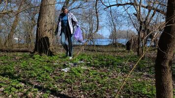 un' volontario uomo raccoglie spazzatura nel un' plastica Borsa nel un' città parco. sicuro ecologia concetto. video