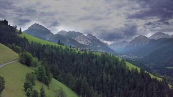 fliegen Über ein klein Berg Dorf im ein schön Ort umgeben durch das Spitzen von das Dolomiten im Italien. 4k video
