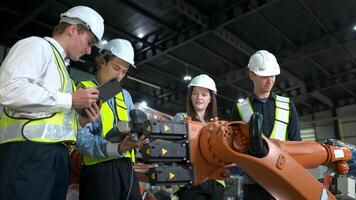 grupo de ingenieros y técnicos trabajando juntos en un robótico brazo fábrica. inspeccionando robot brazo antes de entregando a clientes foto