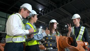 grupo de ingenieros y técnicos trabajando juntos en un robótico brazo fábrica. inspeccionando robot brazo antes de entregando a clientes foto