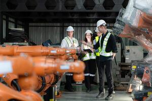 Group of engineers and technicians working together in a robotic arm factory. Inspecting robot arm before delivering to customers photo