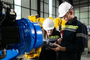 ambos de ingenieros trabajando juntos en un robótico brazo fábrica, robótico brazo industria y Ingenieria concepto. foto